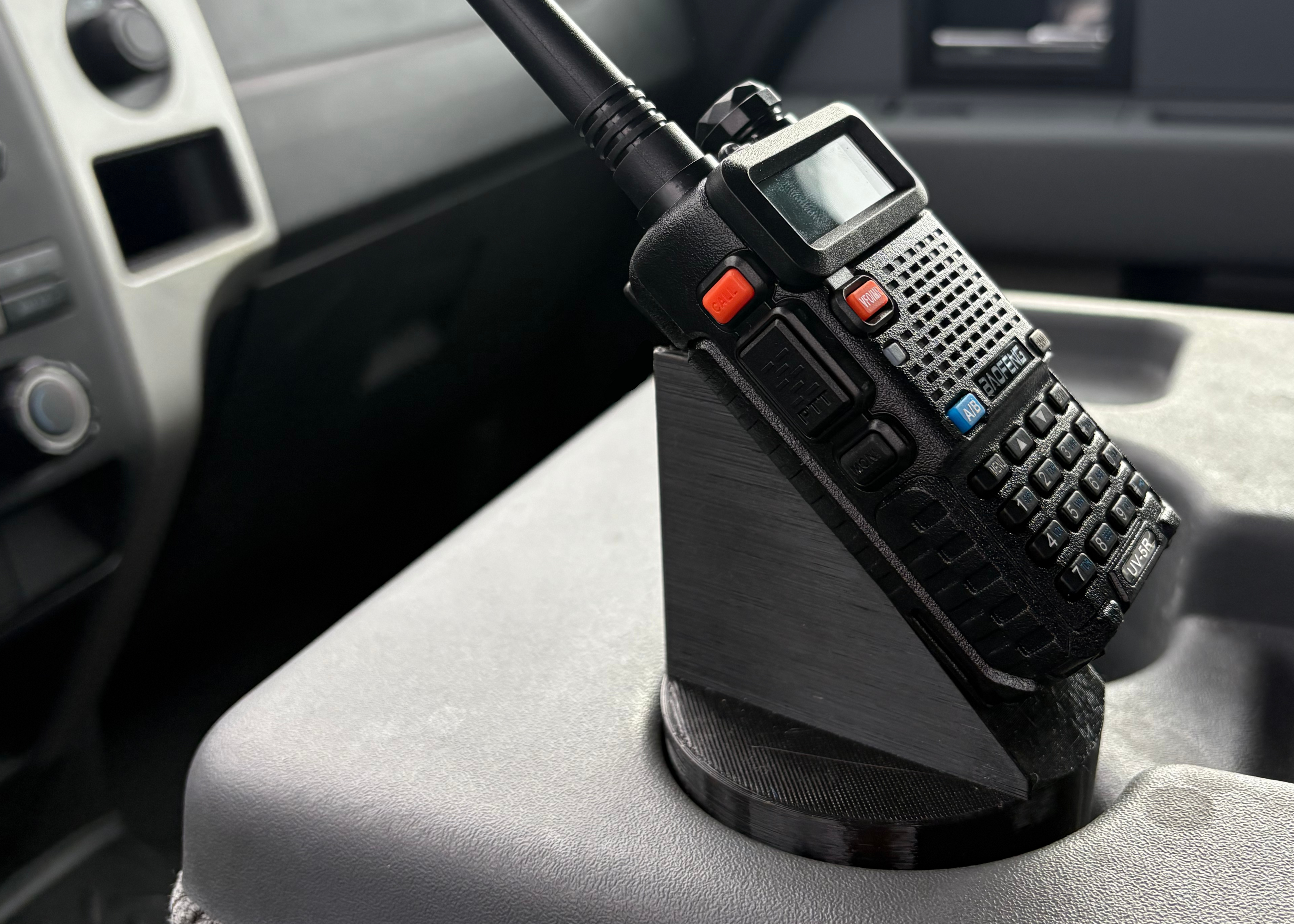 Black walkie-talkie on a car dashboard with a cloudy sky outside.